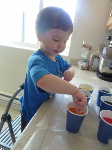 Elias placing an egg in the orange dye