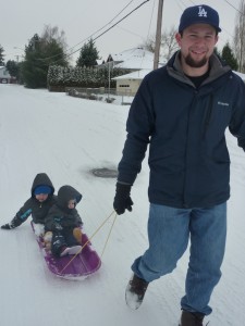 Daddy pulling the boys down a sledding hill.